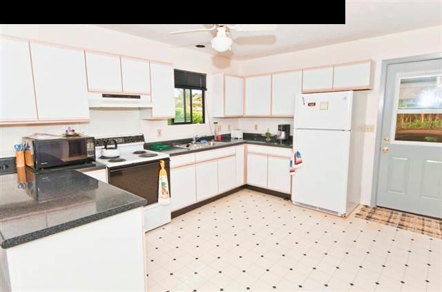 950 Akoa Place Haiku, HI 96708 - Photo 9 of 25 a kitchen with granite countertop a sink a stove a refrigerator and white cabinets