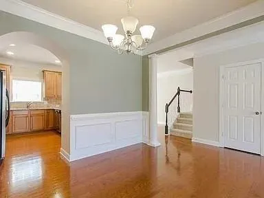 a view of a hallway with wooden floor and a kitchen