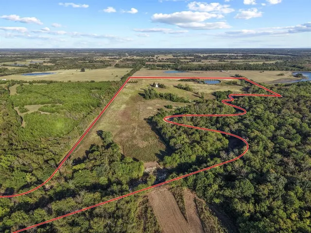 an aerial view of residential houses with outdoor space and trees