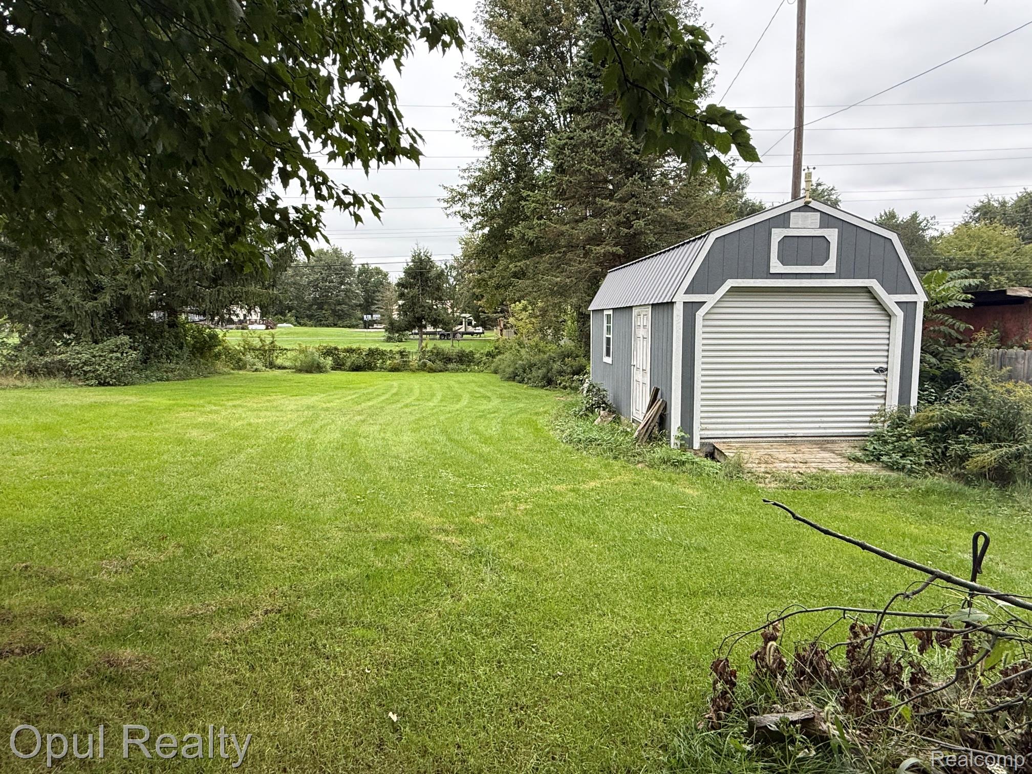 12208 Hannan Road Romulus, MI 48174 - Photo 5 of 15 Expansive green space featuring a detached storage shed with a roll-up door and a side entry door