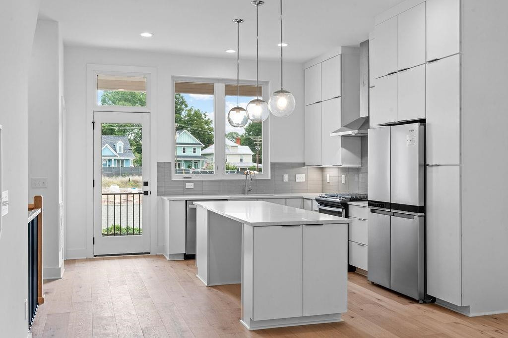 310 Mallard Avenue Durham, NC 27701 - Photo 11 of 41 a kitchen with stainless steel appliances granite countertop a refrigerator a sink dishwasher a stove and a dining table with wooden cabinet