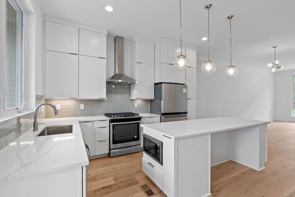 310 Mallard Avenue Durham, NC 27701 - Photo 10 of 41 a kitchen with stainless steel appliances granite countertop a sink a stove a refrigerator a center island a stove and a sink with granite countertops