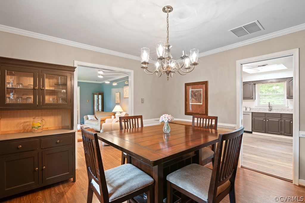 9441 Trails End Road Midlothian, VA 23112 - Photo 8 of 40 a dining room with wooden floor a chandelier a wooden table and chairs