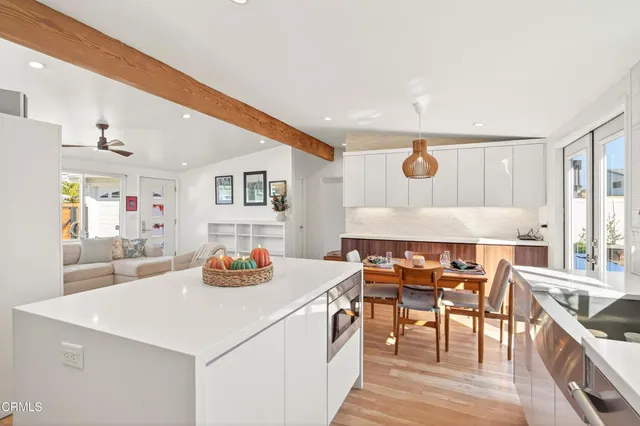 a dining hall with stainless steel appliances kitchen island a table and chairs in it