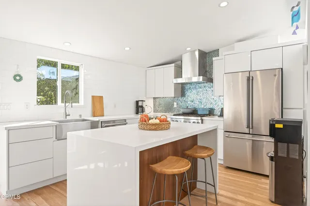a kitchen with a sink a stove a refrigerator and white cabinets