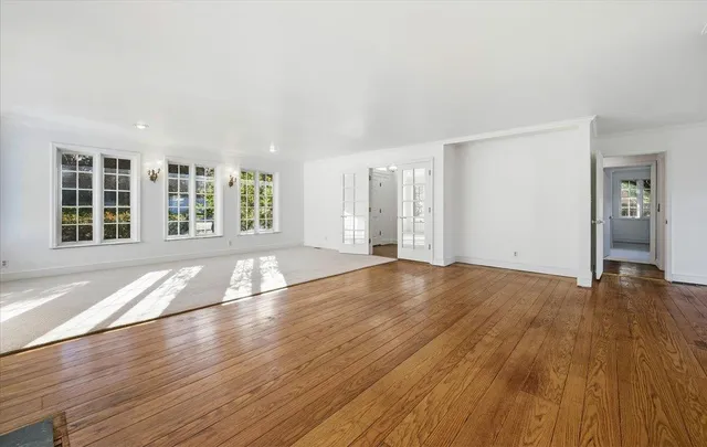 an empty room with wooden floor fireplace and windows