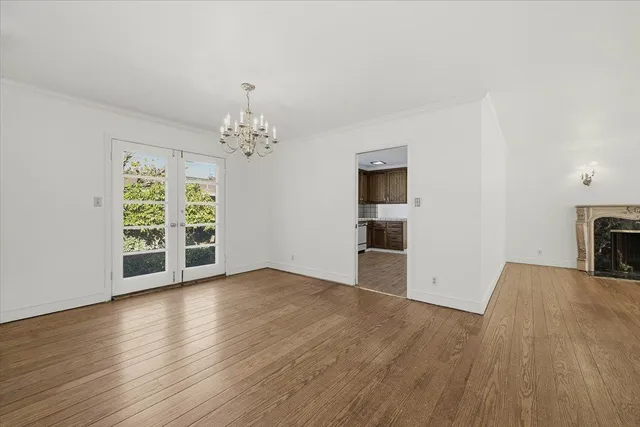 an empty room with wooden floor chandelier and windows