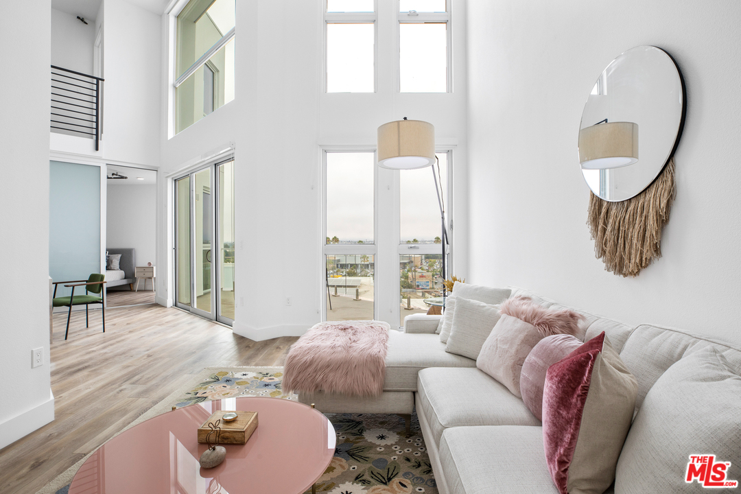 13448 Beach Avenue, Unit PH7314 Marina del Rey, CA 90292 - Photo 5 of 22 a living room with furniture and a large mirror next to a window