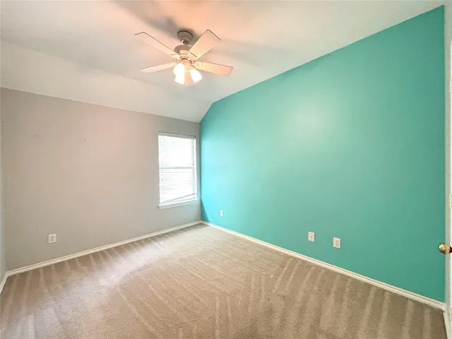 a view of an empty room with chandelier fan and a window