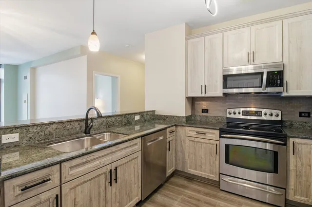 a kitchen with granite countertop white cabinets white stainless steel appliances and a sink