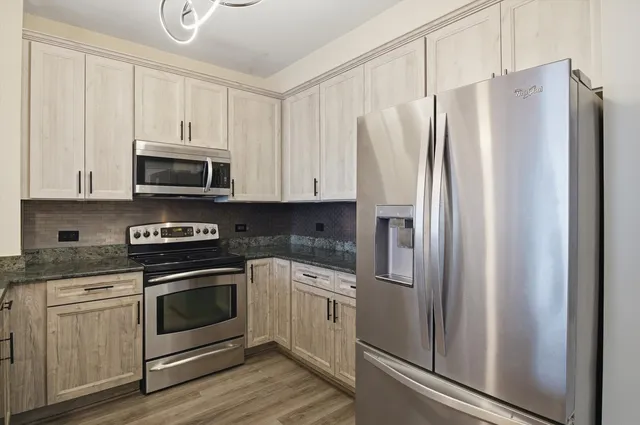 a kitchen with stainless steel appliances white cabinets white stove a microwave and a refrigerator