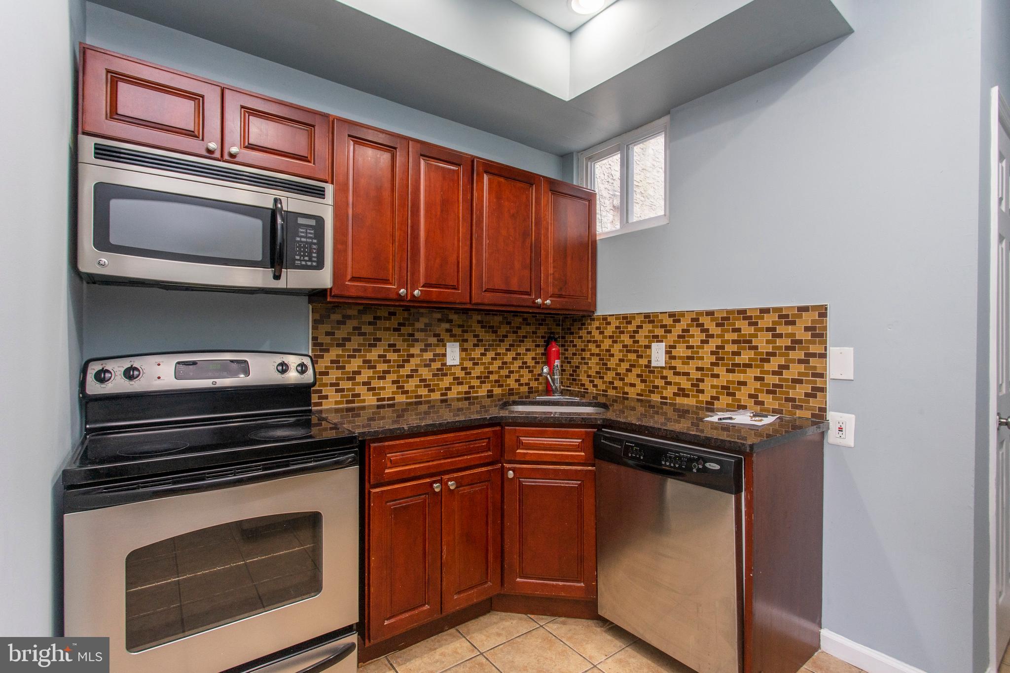 2016 North 18th Street, Unit 2 Philadelphia, PA 19121 - Photo 23 of 23 a kitchen with granite countertop cabinets stainless steel appliances and wooden floor