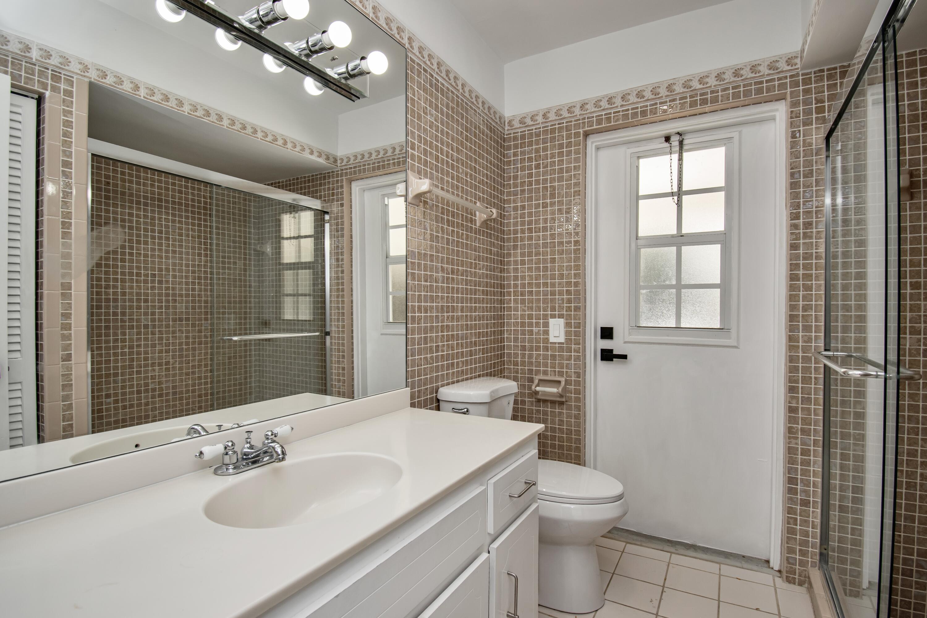 6749 South Grande Drive Boca Raton, FL 33433 - Photo 20 of 35 a bathroom with a toilet a sink a mirror and a shower