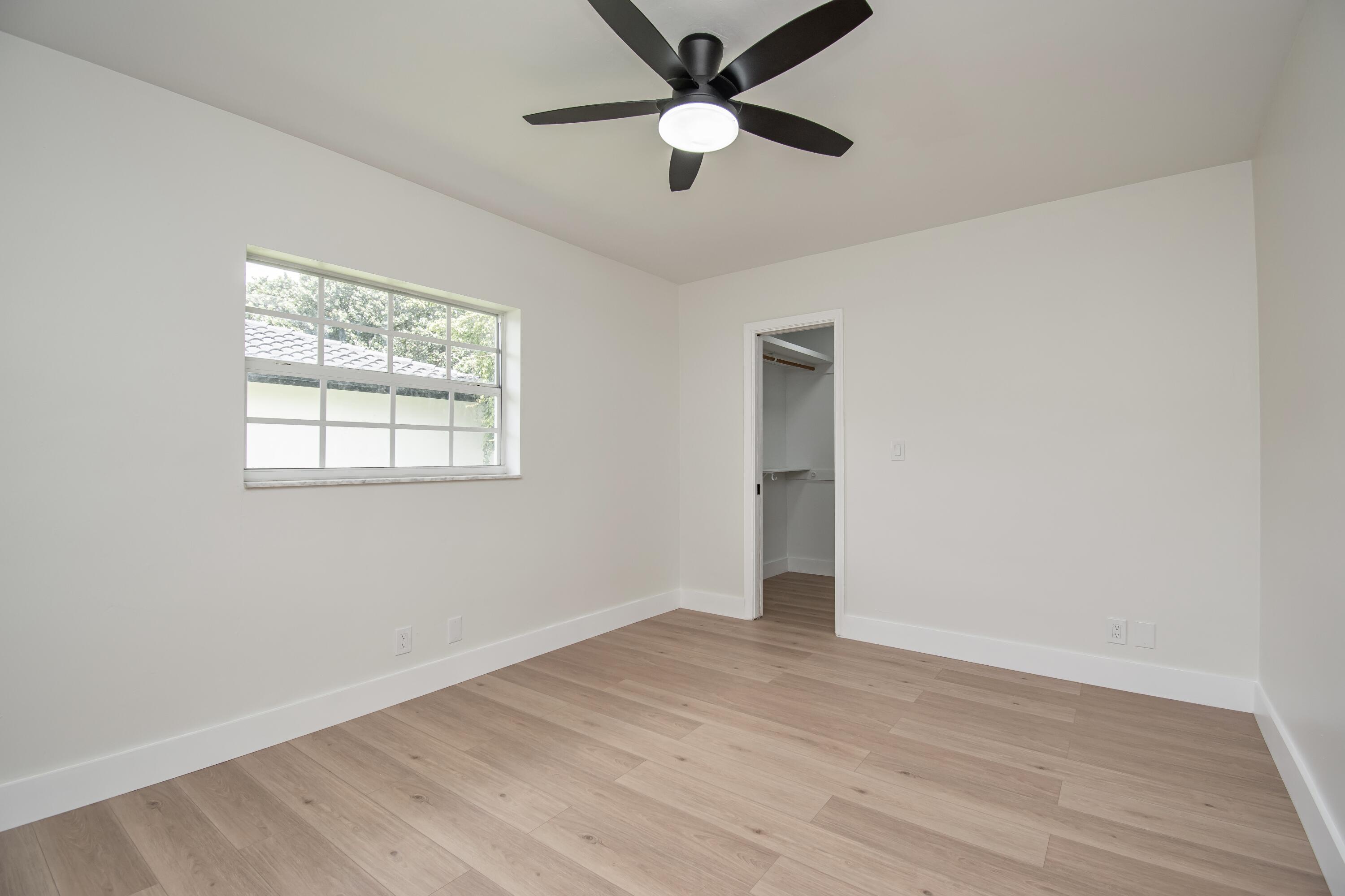 6749 South Grande Drive Boca Raton, FL 33433 - Photo 23 of 35 an empty room with wooden floor ceiling fan and windows