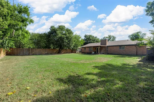 a view of a backyard with a garden and wooden fence