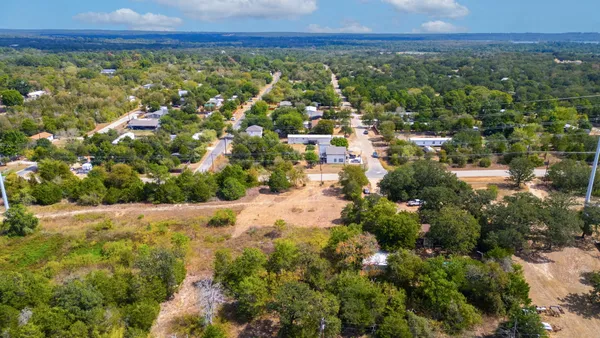 an aerial view of residential houses with outdoor space and trees