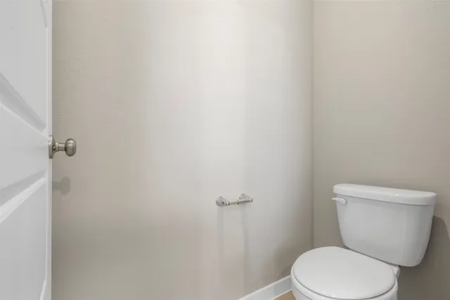 a white toilet sitting next to a white wall