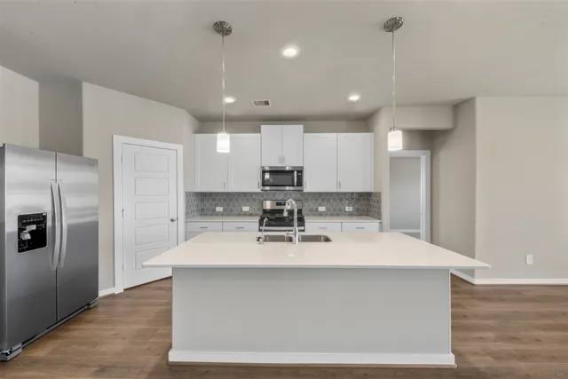 a view of a kitchen with kitchen island a sink stainless steel appliances and cabinets