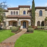 a front view of a house with garden and trees