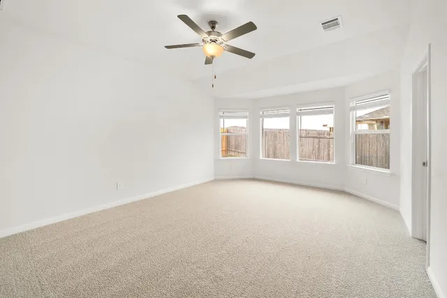 an empty room with a window and a ceiling fan