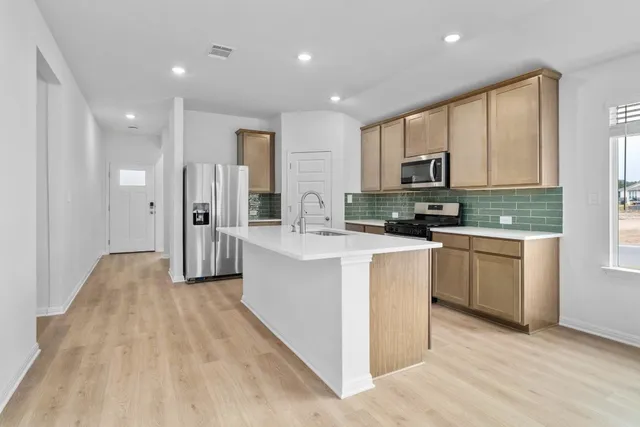 a kitchen with stainless steel appliances granite countertop a refrigerator stove top oven and sink