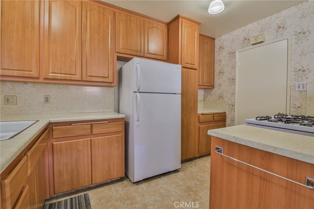 15719 Pitts Avenue Paramount, CA 90723 - Photo 15 of 33 a kitchen with stainless steel appliances granite countertop a refrigerator a stove and a sink with cabinets