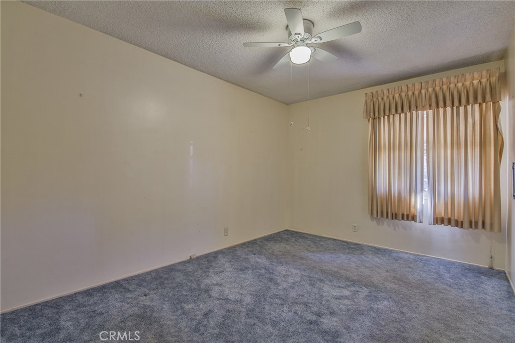 15719 Pitts Avenue Paramount, CA 90723 - Photo 17 of 33 an empty room with a chandelier fan and windows
