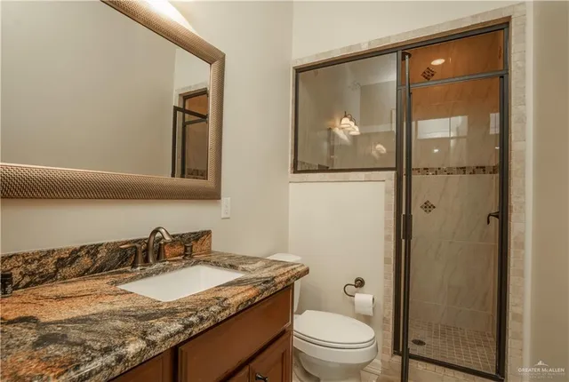 a bathroom with a granite countertop sink toilet and shower