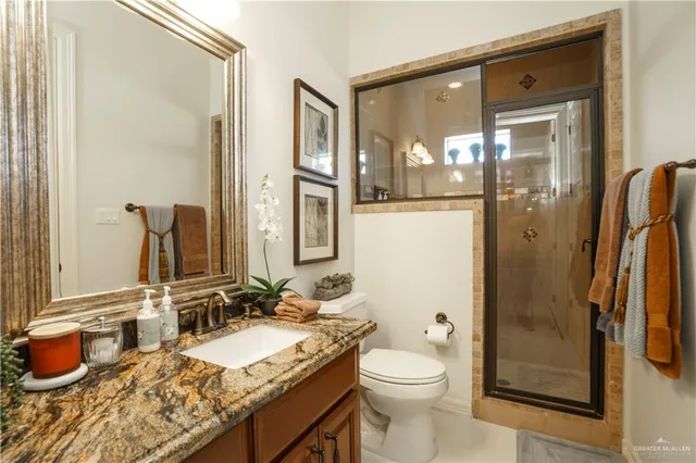 a bathroom with a granite countertop sink toilet and shower