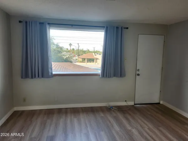 a view of an empty room with wooden floor and a window