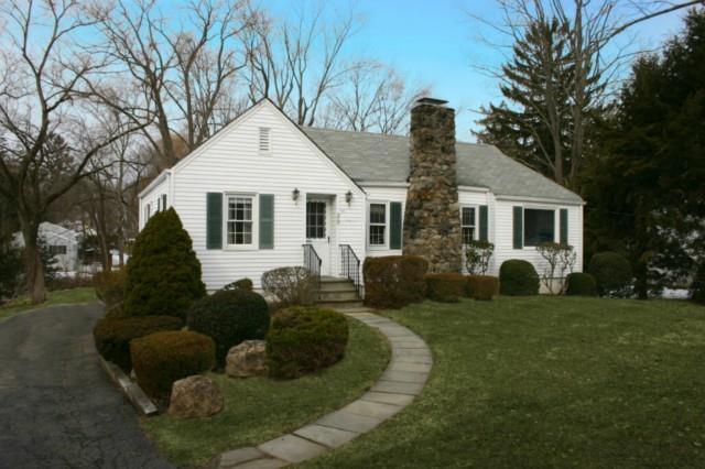 a front view of a house with a garden and trees
