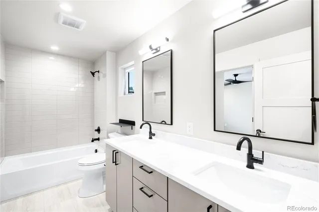 a bathroom with a double vanity sink toilet mirror and bathtub