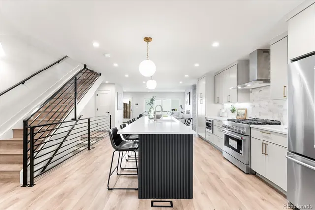 a kitchen with stainless steel appliances kitchen island granite countertop a stove a sink dishwasher and a refrigerator with wooden floor