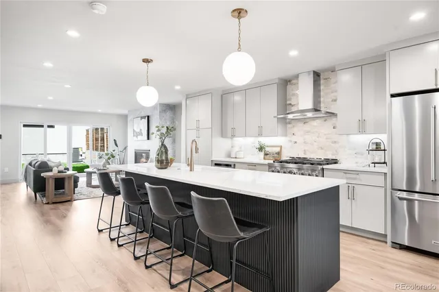 a kitchen with stainless steel appliances a dining table chairs stove refrigerator and cabinets