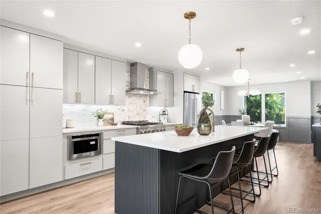 a kitchen with stainless steel appliances kitchen island granite countertop a sink a stove a dining table and chairs