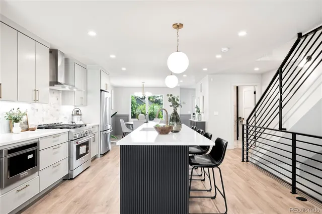 a kitchen with stainless steel appliances kitchen island granite countertop a stove a sink a dining table and chairs with wooden floor