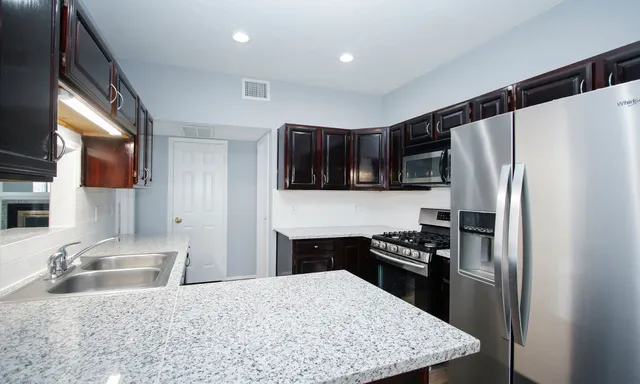 a kitchen with granite countertop a refrigerator stove and sink