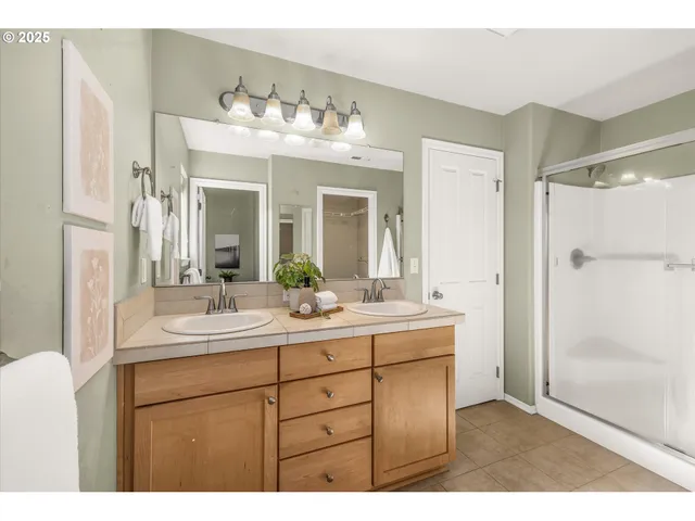 a bathroom with a double vanity sink mirror and shower