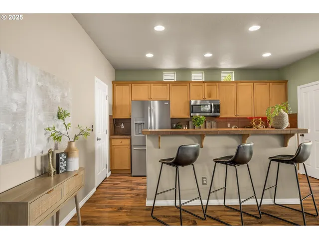 a kitchen with stainless steel appliances kitchen island granite countertop a refrigerator a stove a sink and a counter space