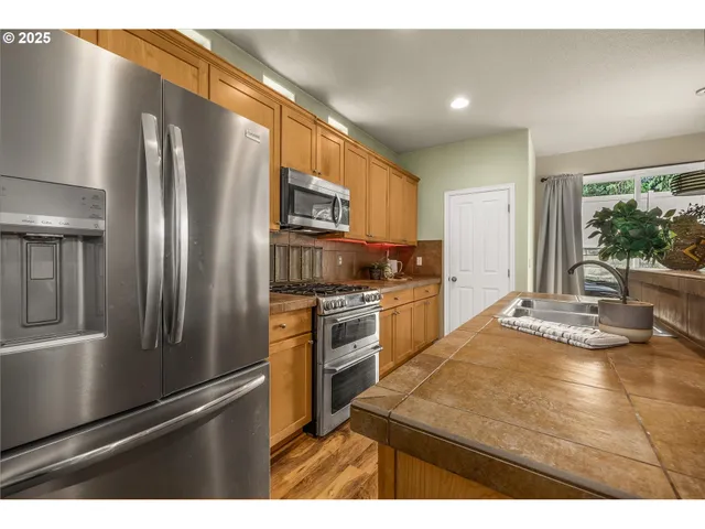 a kitchen with stainless steel appliances granite countertop a refrigerator a stove and a sink