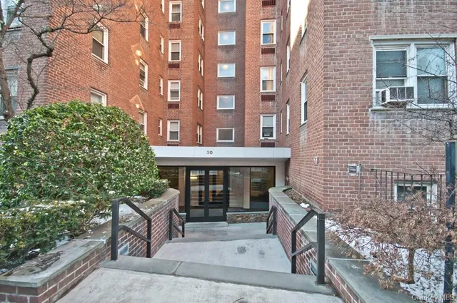 front view of a brick house with a large tree
