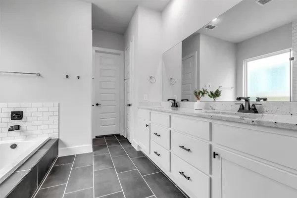 a spacious bathroom with a double vanity sink a mirror and a bathtub