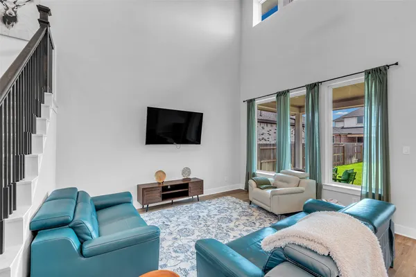 a living room with furniture floor to ceiling window hardwood floor and a flat screen tv