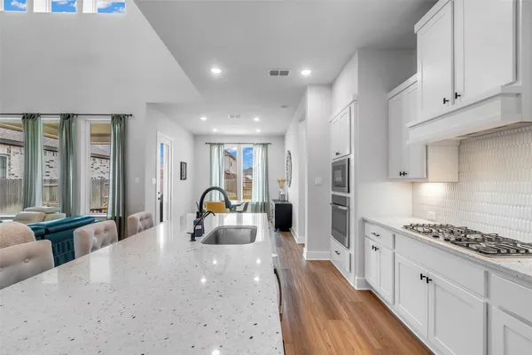 a large kitchen with stainless steel appliances a large counter top a stove and a refrigerator