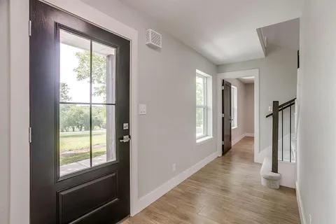a view of hallway with window and wooden floor