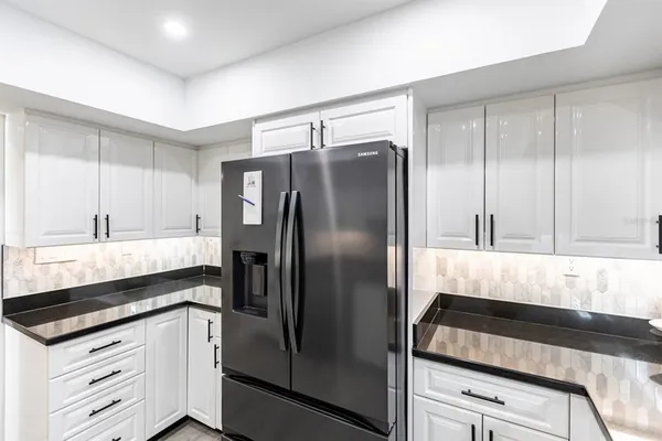 a kitchen with granite countertop a refrigerator and a sink