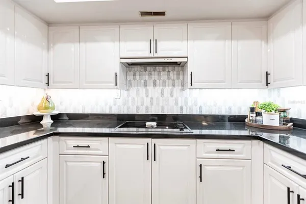 a kitchen with granite countertop white cabinets and black appliances
