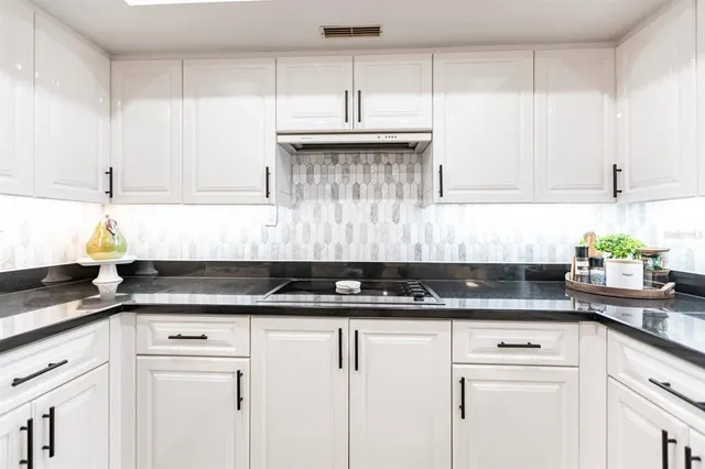 a kitchen with granite countertop white cabinets and black appliances