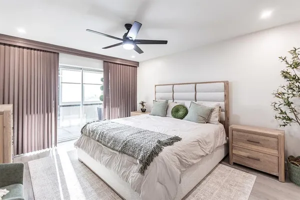 a bedroom with a large bed and a chandelier fan