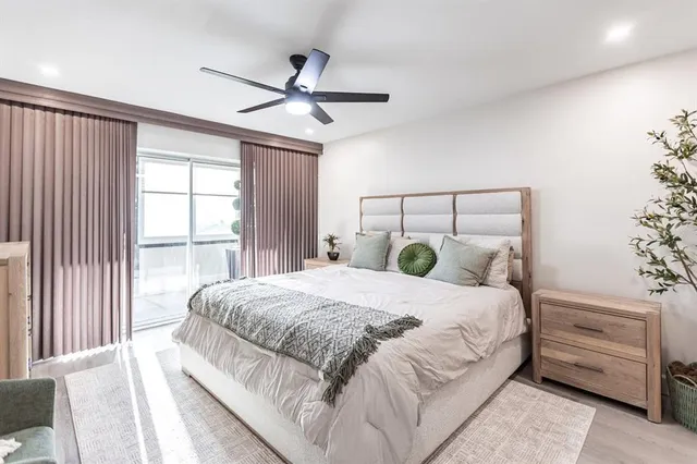 a bedroom with a large bed and a chandelier fan